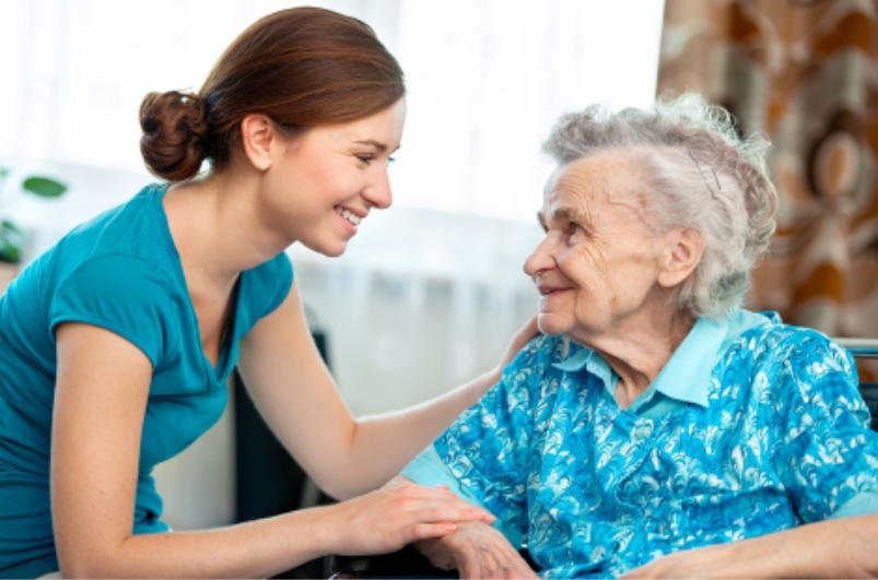 Caregiver in a teal shirt caring for an elderly woman